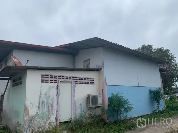 คลังสินค้า ให้เช่าในLam Luk Ka, Pathum Thani - ด้านนอกโกดัง ผนังเมทัลชีท มีคอมเพรสเซอร์แอร์ จานดาวเทียม และสีอาคารที่ซีดจาง