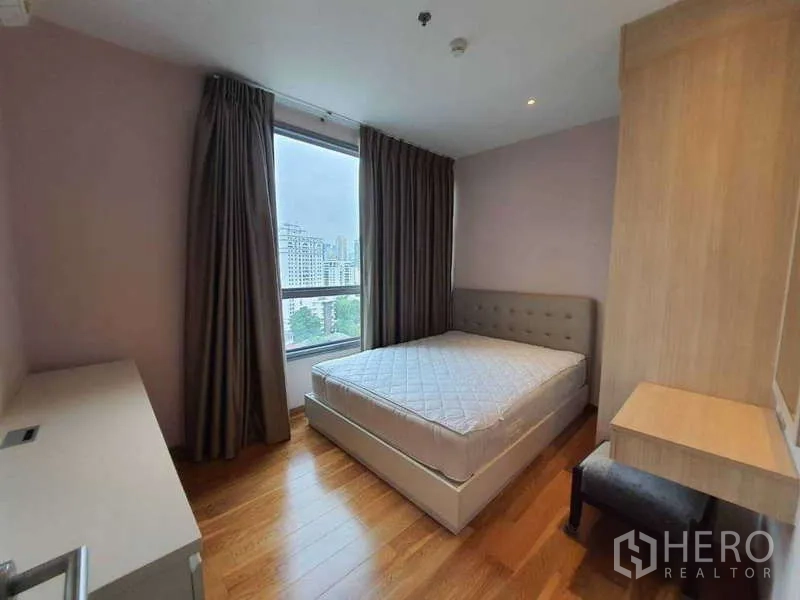 公寓 出售在Watthana, Bangkok - 转角卧室配大窗与双人床，欣赏城市景致。