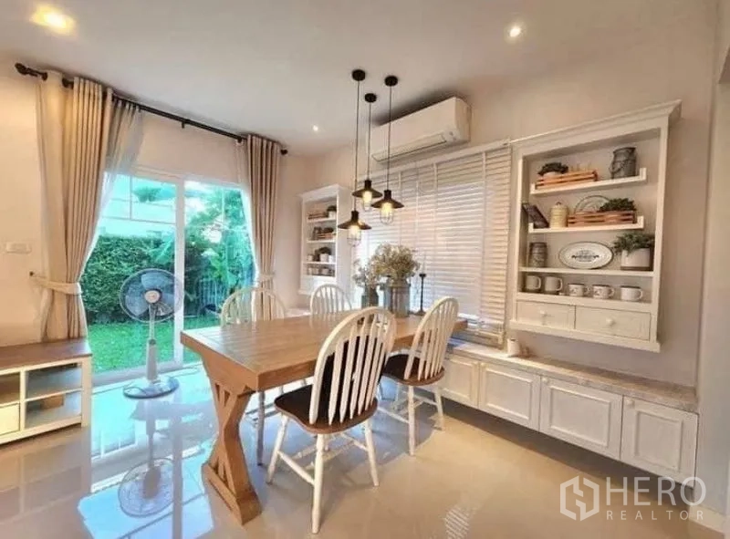 Detached House for rent in Bang Bo, Samut Prakan - Dining room with built-in cabinetry and sliding doors opening to the lawn.