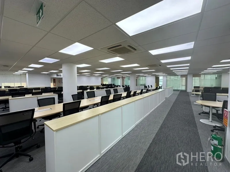 Office Space for rent - Large workstation area with rows of desks and task chairs under LED panels.