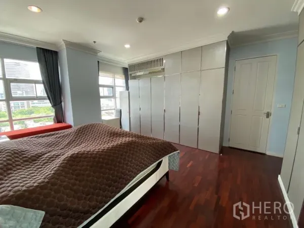 คอนโด ให้เช่าในRatchathewi, Bangkok - ห้องนอนมาสเตอร์มุมอาคาร มีหน้าต่างมองวิวเมืองและตู้เสื้อผ้าสูงจรดเพดาน