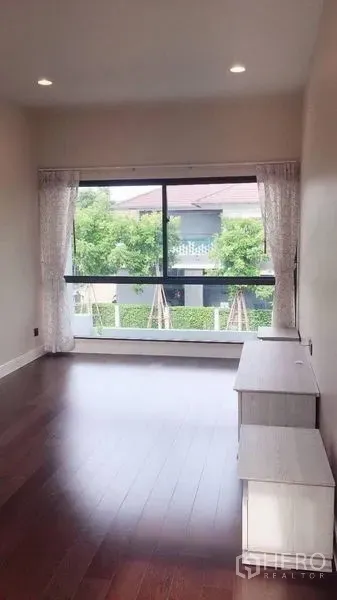 Detached House for rent in Bang Kapi, Bangkok - Light-filled multipurpose room with a wide window, curtains and timber floors.