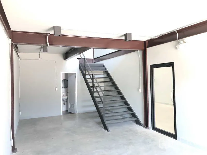 货栈 出租在Bang Phli, Samut Prakan - 一层办公区，带金属楼梯、混凝土地面和卫生间门。