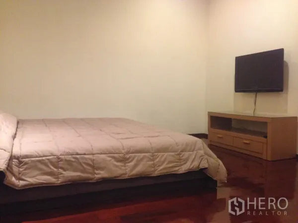 คอนโด ให้เช่าในWatthana, Bangkok - ห้องนอนพร้อมเตียงขนาดใหญ่ ทีวีติดผนัง และตู้วางทีวีไม้บนพื้นไม้มันวาว