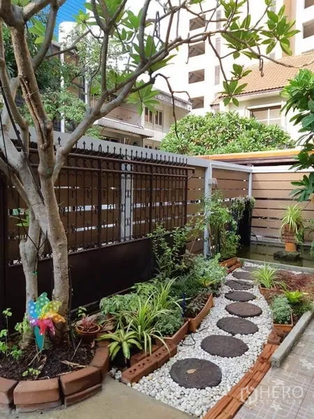 บ้าน ให้เช่าในWatthana, Bangkok - สวนขนาดกะทัดรัด ทางเดินแผ่นหินโรยกรวดสีขาว พร้อมไม้ใบเขตร้อนข้างรั้ว