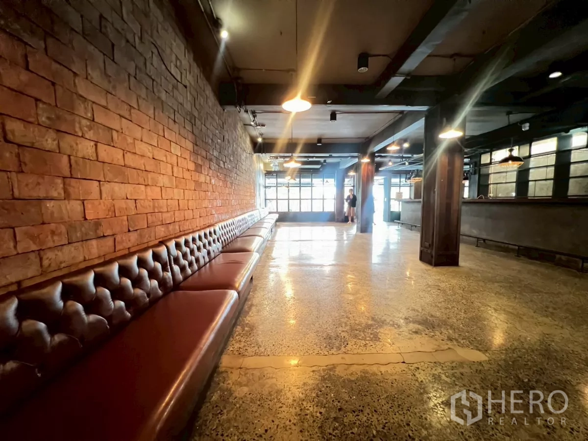零售空间 出租 - 开阔就餐区，裸露红砖墙、长条皮椅与抛光水泥地面。