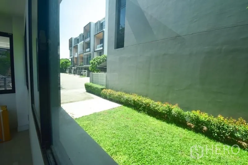 ทาวน์เฮาส์ ให้เช่าหรือขายในSuan Luang, Bangkok - มุมมองจากหน้าต่างเห็นสนามหญ้าส่วนตัวและแถวทาวน์โฮมในวันแดดจัด