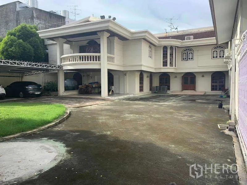 Detached House for sale in Huai Khwang, Bangkok - Front view of the detached house with covered parking and green lawn.