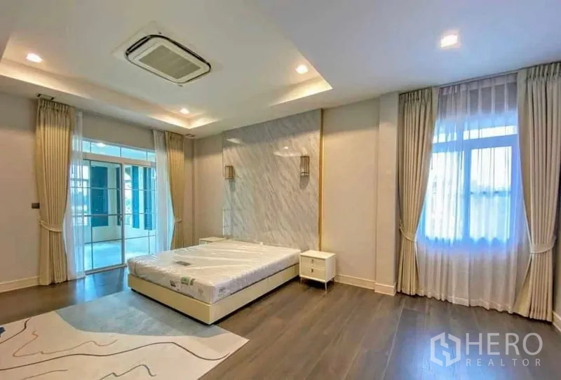 Detached House for rent in Bang Khen, Bangkok - Primary bedroom with marble accent wall, tray ceiling and balcony access.