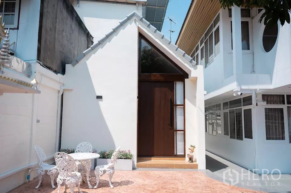 บ้าน ให้เช่าในPhra Khanong, Bangkok - ภาพใกล้ของหน้าบ้านสีขาวสมัยใหม่และประตูทางเข้าติดลานบ้าน