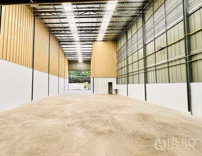 Warehouse for rent in Pak Kret, Nonthaburi - Clear-span interior facing the entrance, steel trusses and bright strip lighting.