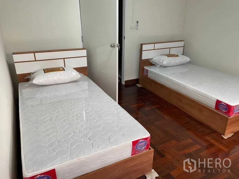 Home Office for rent or sale in Watthana, Bangkok - Second twin-bed room with white walls and parquet flooring.