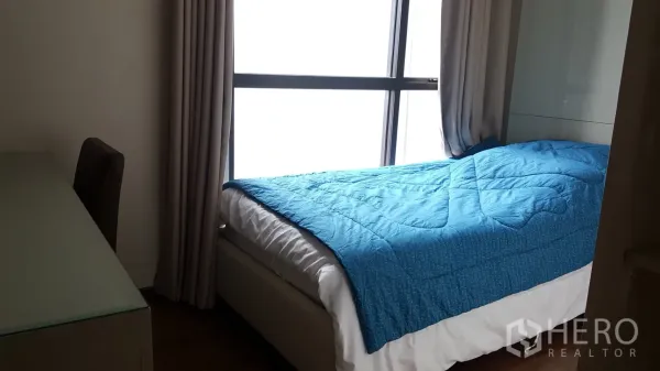 公寓 出租或出售在Khlong Toei, Bangkok - 次卧设单人床、蓝色被子，临全景窗并配有书桌。