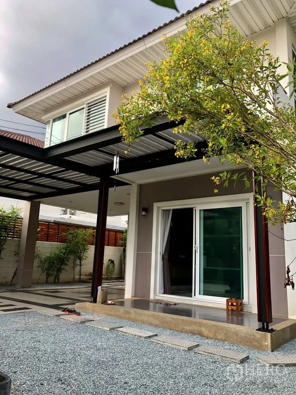 Detached House for rent or sale in Bang Phli, Samut Prakan - Front porch with sliding glass door, metal carport roof and landscaped gravel yard.