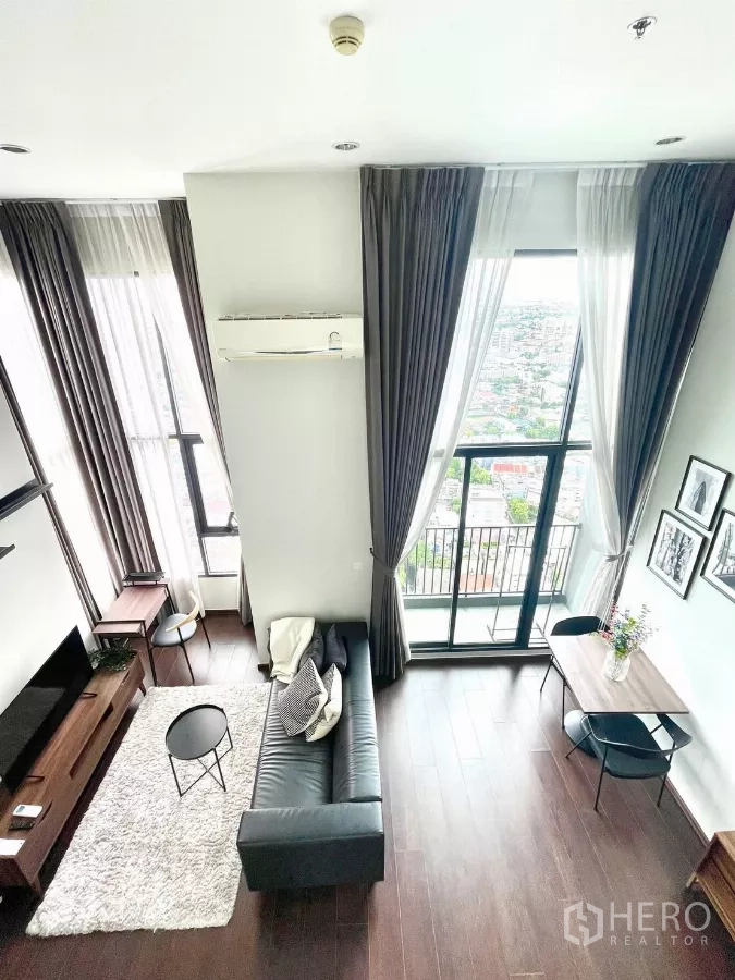 Condominium for rent in Watthana, Bangkok - Open living area facing a balcony with panoramic city view and a small dining table.