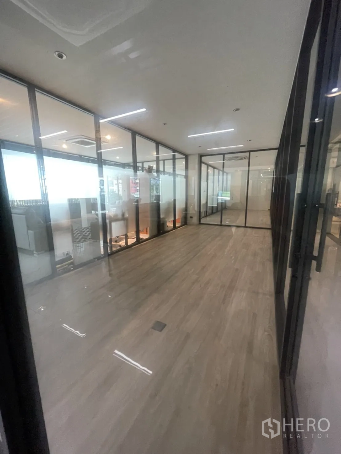 สำนักงาน ให้เช่าในLam Luk Ka, Pathum Thani - โถงทางเดินผนังกระจก พื้นลามิเนตลายไม้ และไฟเส้น LED