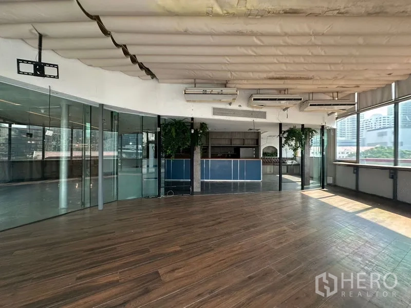 零售空间 出租在Pathum Wan, Bangkok - 开放式空间带吧台、玻璃隔断及绿植点缀。