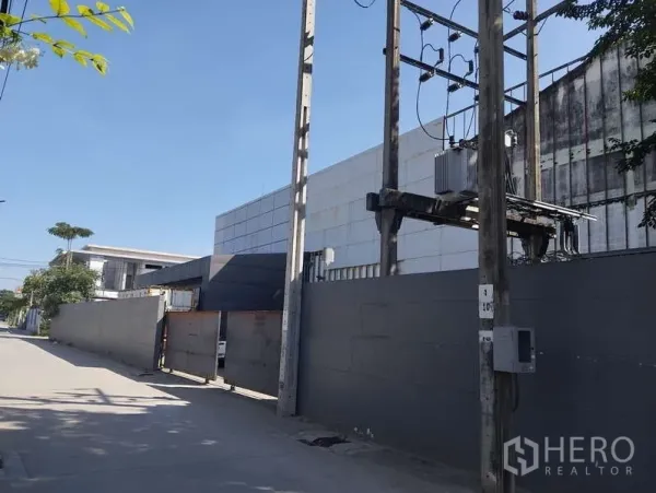 โรงงาน ขายในSaphan Sung, Bangkok - ทางเข้าโรงงาน มีกำแพงสูงและหม้อแปลงไฟฟ้าหน้าพื้นที่ ติดถนนคอนกรีตกว้าง