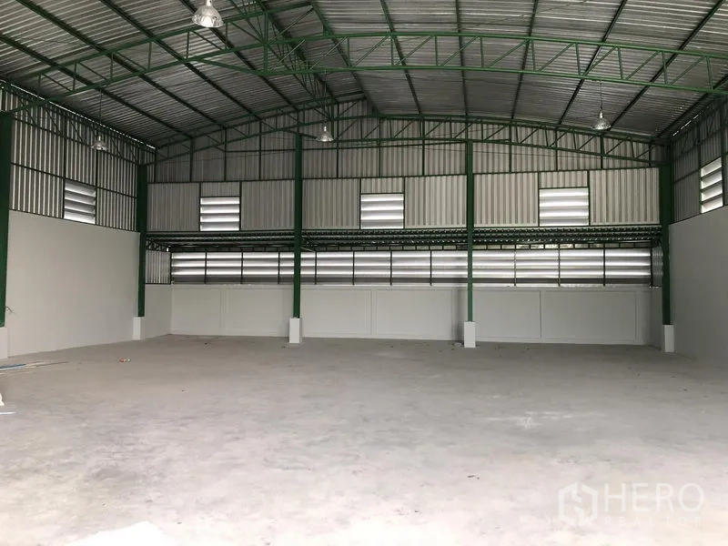 Factory for rent or sale in Khlong Luang, Pathum Thani - Spacious warehouse bay with steel truss roof, ventilation panels and smooth concrete floor.