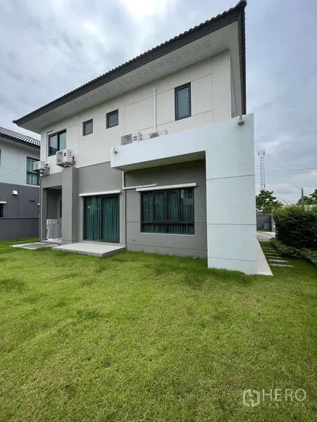 Detached House for rent in Don Mueang, Bangkok - Rear façade of the home with green lawn and garden.
