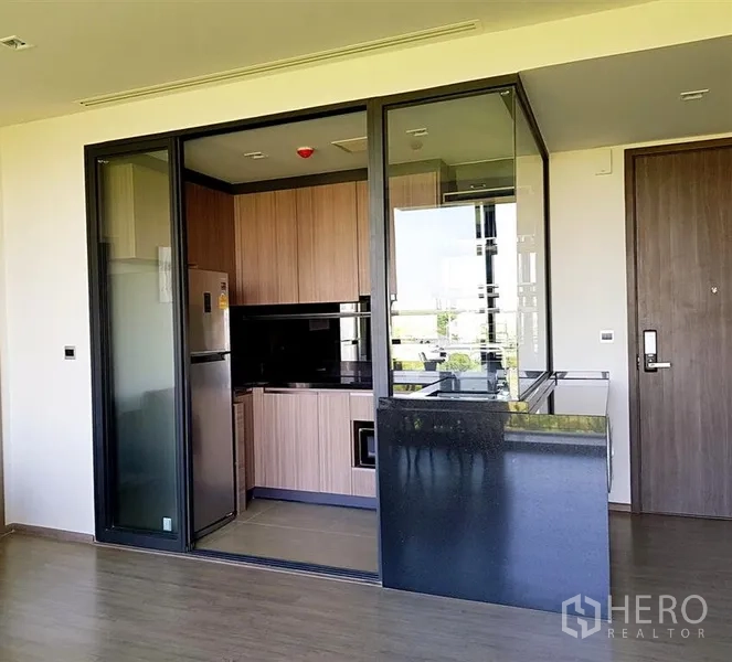 Condominium for rent in Watthana, Bangkok - Enclosed kitchen with glass partitions, wood cabinets, and stainless refrigerator.