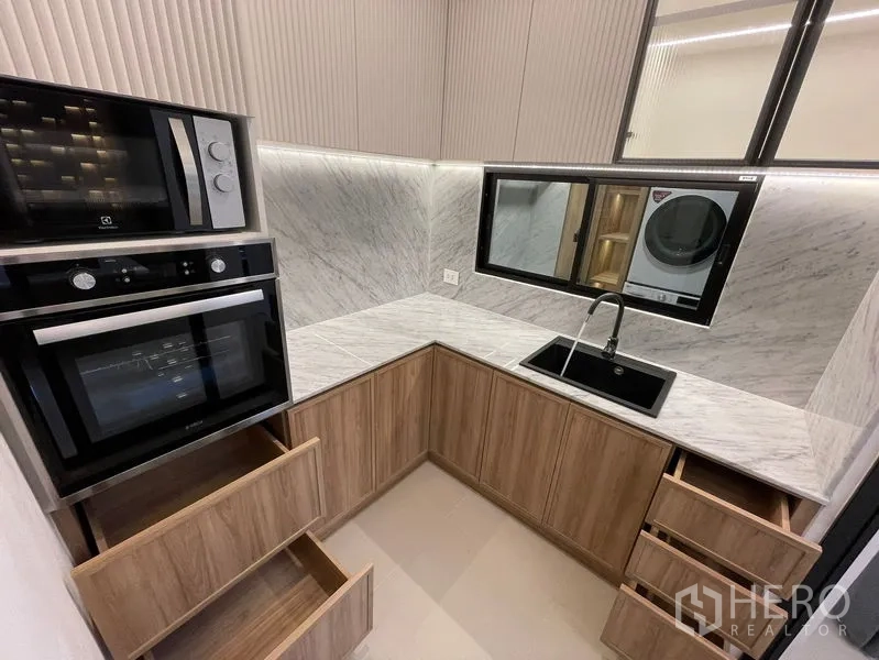Townhouse for sale - Compact U‑shaped kitchen with marble backsplash, black sink and built‑in oven and microwave.