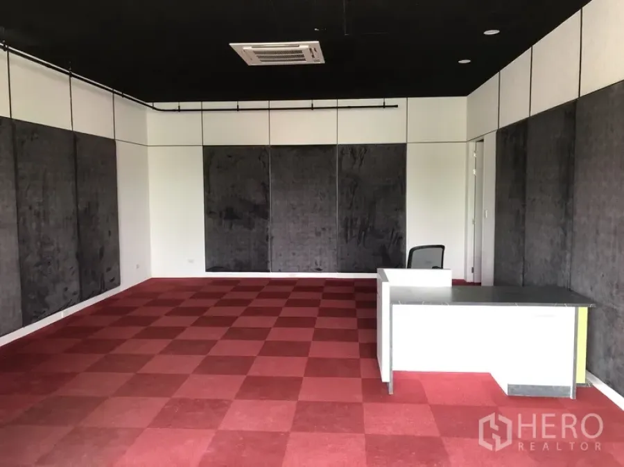 Office Space for rent in Wang Thonglang, Bangkok - Open-plan 60 sqm office with red checkered carpet, acoustic wall panels, black ceiling with cassette AC, and a reception desk in Wang Thonglang, Bangkok.