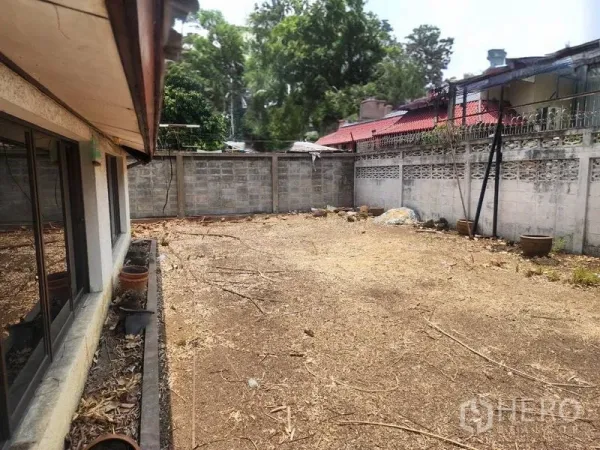 Detached House for rent in Watthana, Bangkok - Walled side yard with bare soil beside the house, ideal for garden or parking.
