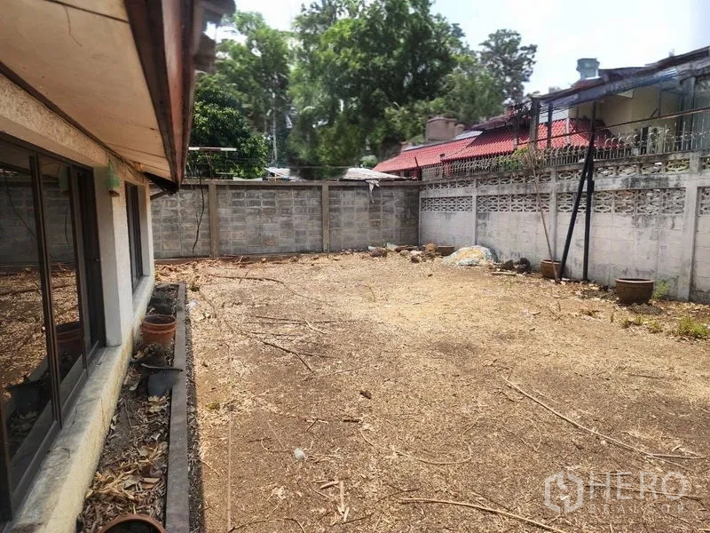 Detached House for rent in Watthana, Bangkok - Walled side yard with bare soil beside the house, ideal for garden or parking.