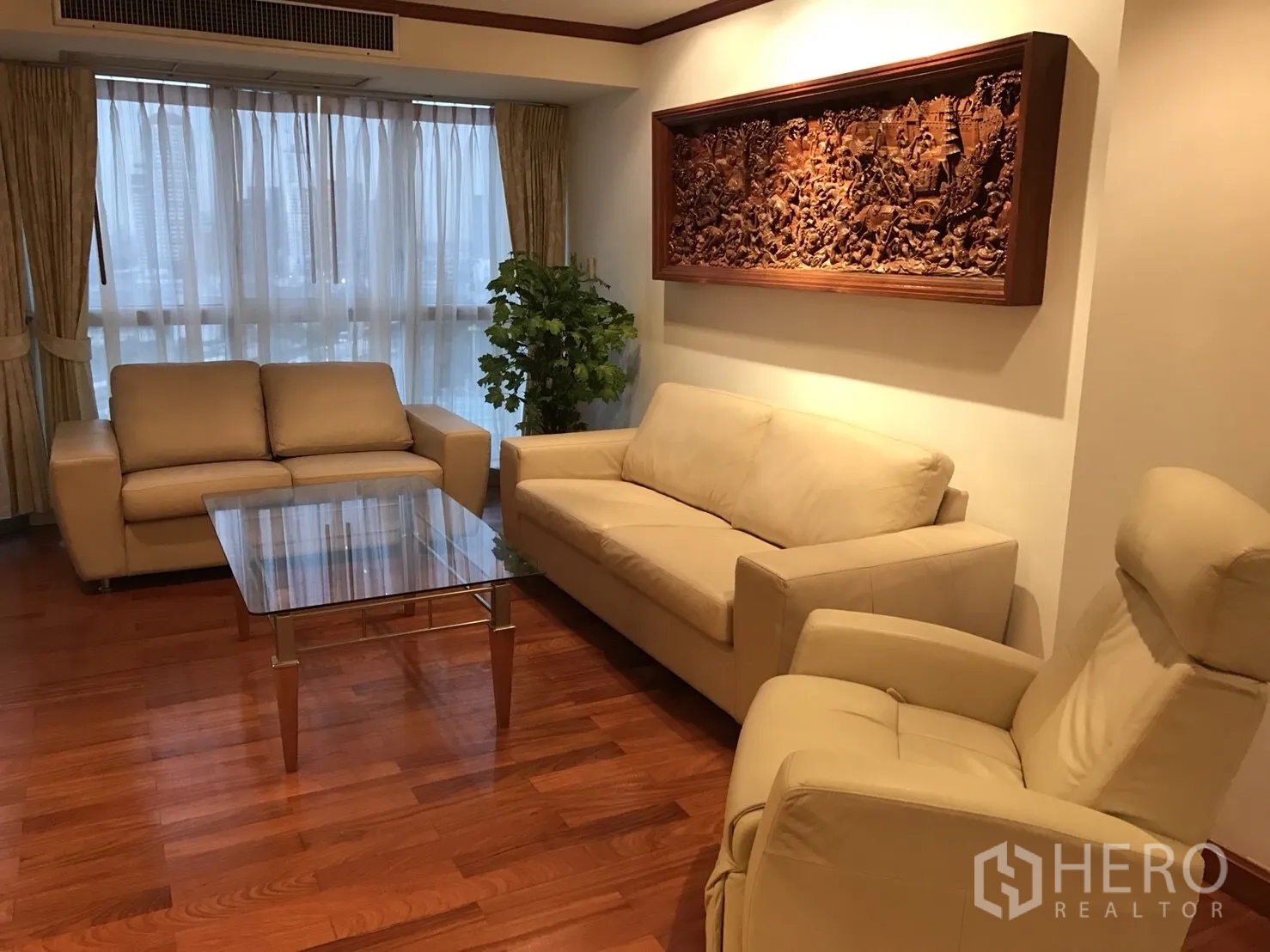 公寓 出租在Khlong Toei, Bangkok - 客厅配米色皮沙发、玻璃茶几与大落地窗。