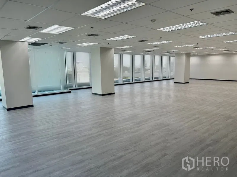 Office Space for rent in Sathon, Bangkok - Bright open‑plan office in Sathon with light wood flooring, grid ceiling lighting, columns, and full‑height windows with city views.