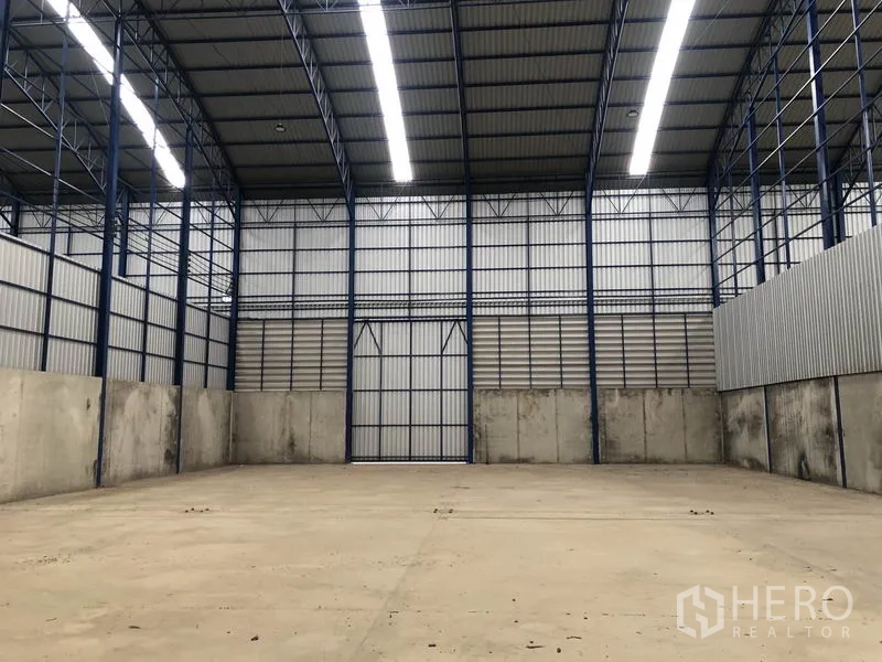 Warehouse for rent in Lat Lum Kaeo, Pathum Thani - Spacious warehouse interior with high arched roof, steel columns, LED strip lighting and large double doors.