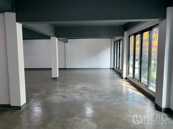 อาคารพาณิชย์ ให้เช่าในKhlong Toei, Bangkok - พื้นที่ค้าปลีกแบบโอเพ่นสเปซ พื้นปูนขัดมัน ผนังสีขาว และหน้าต่างสูงเต็มบานรับแสงธรรมชาติ