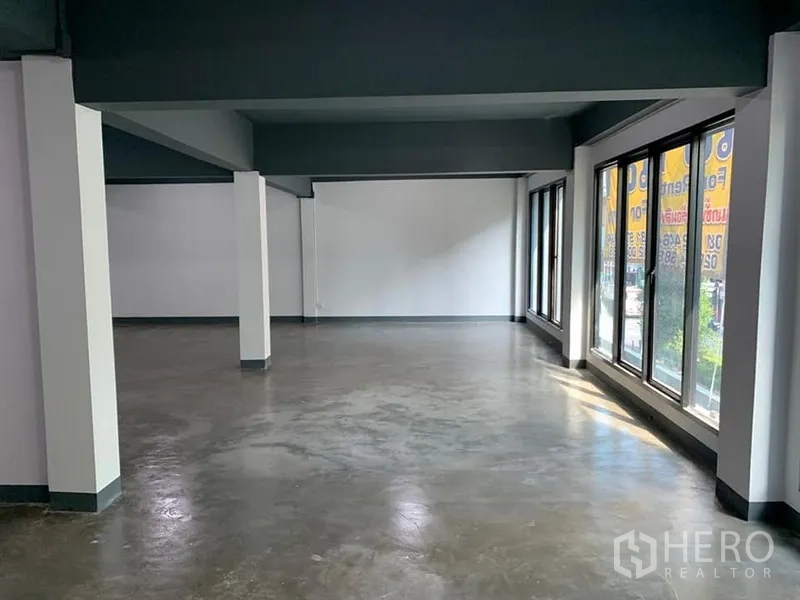 อาคารพาณิชย์ ให้เช่าในKhlong Toei, Bangkok - พื้นที่ค้าปลีกแบบโอเพ่นสเปซ พื้นปูนขัดมัน ผนังสีขาว และหน้าต่างสูงเต็มบานรับแสงธรรมชาติ
