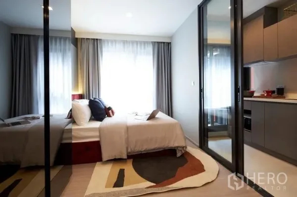 公寓 出售在Ratchathewi, Bangkok - 明亮卧室，大窗户、镜面衣柜与玻璃滑门隔断。