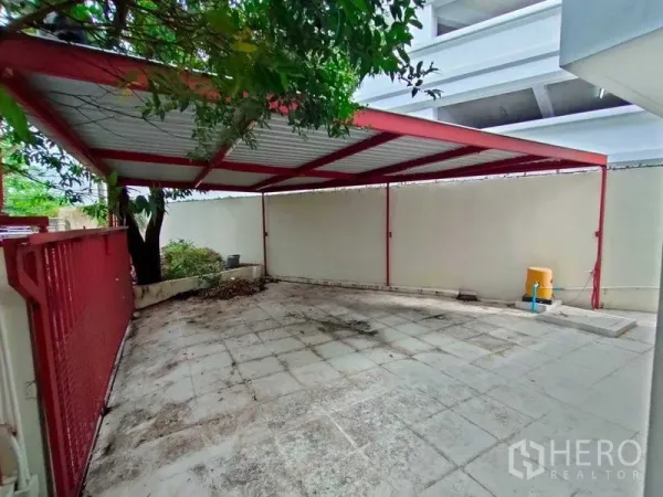 ทาวน์เฮาส์ ให้เช่าในKhlong Toei, Bangkok - ที่จอดรถมีหลังคาโครงเหล็กสีแดง พร้อมลานกระเบื้องและกำแพงสูง