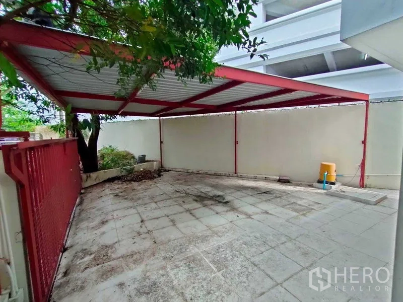 ทาวน์เฮาส์ ให้เช่าในKhlong Toei, Bangkok - ที่จอดรถมีหลังคาโครงเหล็กสีแดง พร้อมลานกระเบื้องและกำแพงสูง