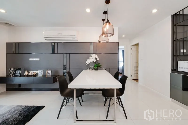 Condominium for sale in Bang Rak, Bangkok - Sleek dining space with a white table, black chairs, designer pendant lighting, and built-in cabinetry.