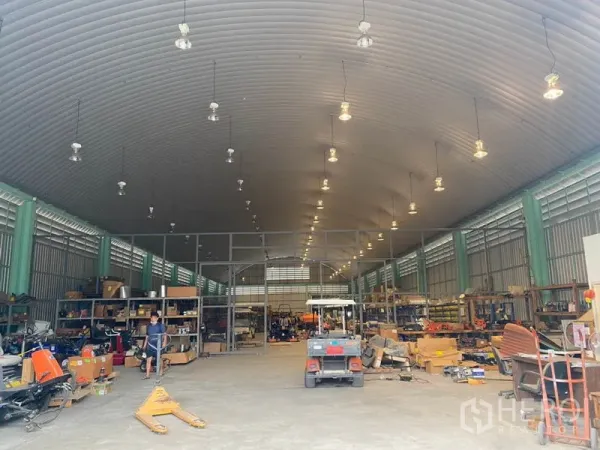 货栈 出租在Lak Si, Bangkok - 仓库内部高挑拱形天花，吊灯照明，金属货架与设备存储区。