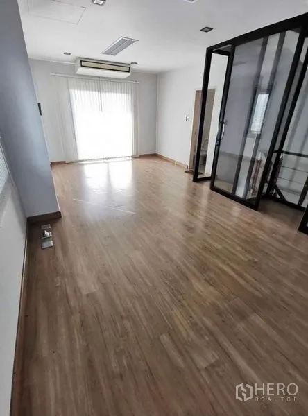 Home Office for rent in Prawet, Bangkok - Spacious upper-floor room with balcony door, wood floors, and glass-partitioned landing