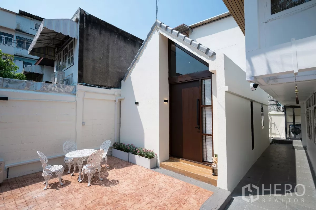 บ้าน ให้เช่าในPhra Khanong, Bangkok - บ้านเดี่ยวหน้าจั่วสีขาว ประตูไม้สูง ลานอิฐกลางแจ้งพร้อมชุดโต๊ะสนาม