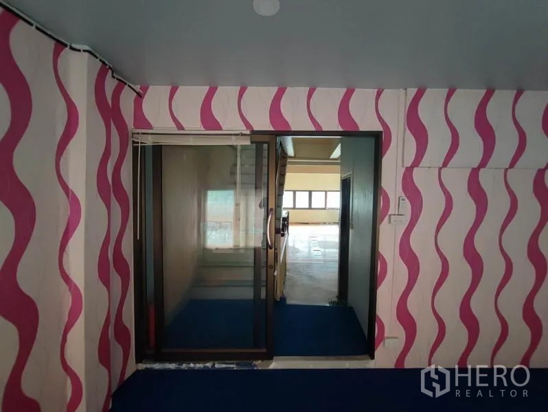 Shophouse for rent in Khlong Toei, Bangkok - Glass sliding door entry framed by pink wavy wallpaper and blue carpet.
