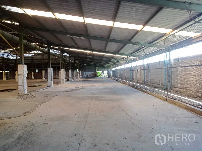 工厂 出租在Lat Lum Kaeo, Pathum Thani - 带顶装卸与缓冲区，长混凝土车道，侧面为铁丝网与通风屋顶。