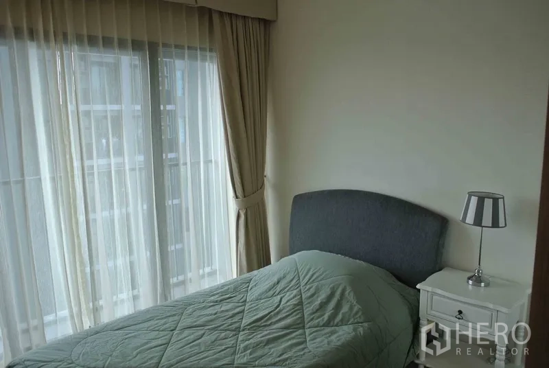 คอนโด ให้เช่าในKhlong Toei, Bangkok - ห้องนอนอบอุ่น ผนังกระจกสูงเต็มบาน ม่านโปร่ง และโต๊ะข้างเตียง