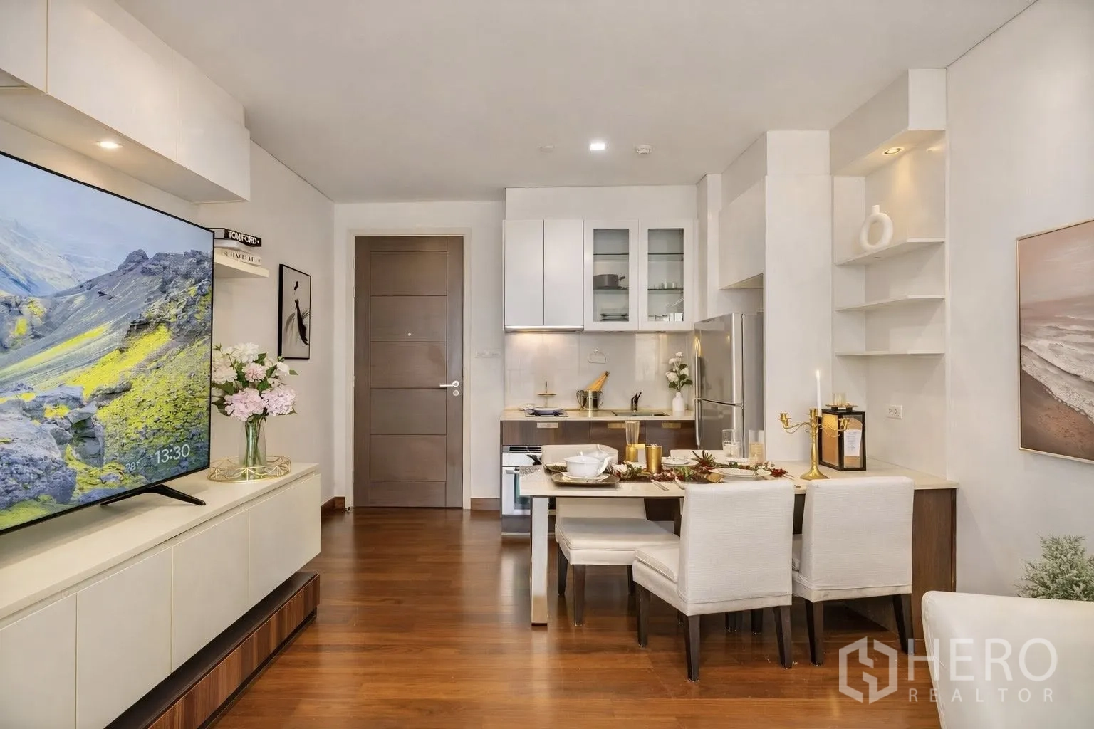 Condominium for rent or sale in Watthana, Bangkok - Dining area facing a compact kitchen and entrance, with wood floors and shelving.