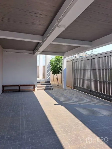 Detached House for rent in Prawet, Bangkok - Covered carport with tiled floor and metal sliding gate at the entrance.