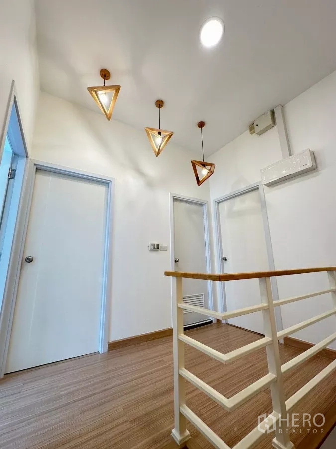 ทาวน์เฮาส์ ให้เช่าในBang Phli, Samut Prakan - โถงชั้นบนพร้อมโคมไฟทรงเรขาคณิตและประตูห้องนอน