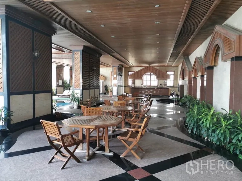 Condominium for rent in Watthana, Bangkok - Shaded leisure area with wooden tables and chairs beside the pool.