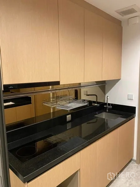 คอนโด ขายในWatthana, Bangkok - ครัวแบบแกลลีย์ท็อปหินแกรนิตสีดำ เตาไฟฟ้า ผนังกระจก และตู้เก็บของครบ