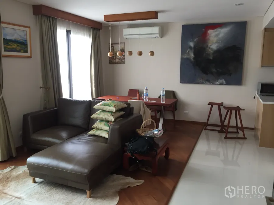 公寓 出租在Ratchathewi, Bangkok - 采光良好的客厅，木地板、皮沙发、餐桌与吊灯，大幅落地窗。